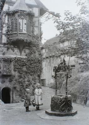 Zwei Kinder im romanischen Kostüm am Brunnen im ersten Burghof